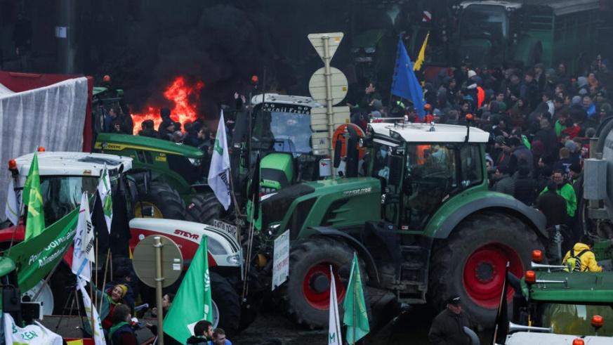 People gather as Belgian farmers use their tractors to block the European Union headquarters, as they protest over price pressures, taxes and green regulation, grievances shared by farmers across Euro