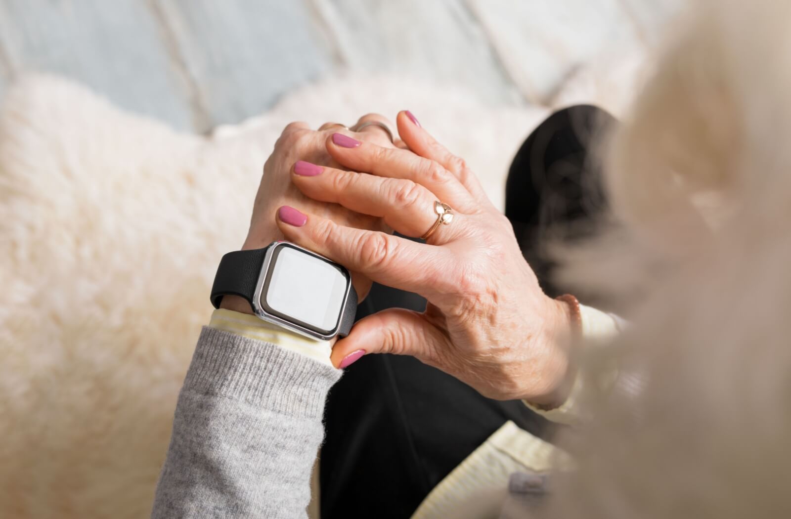 An older adult woman interacting with her smartwatch.