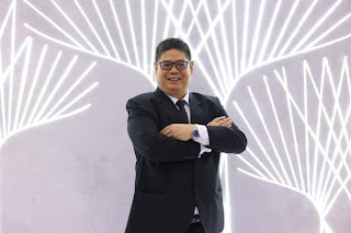 A person in a suit with his arms crossed

Description automatically generated