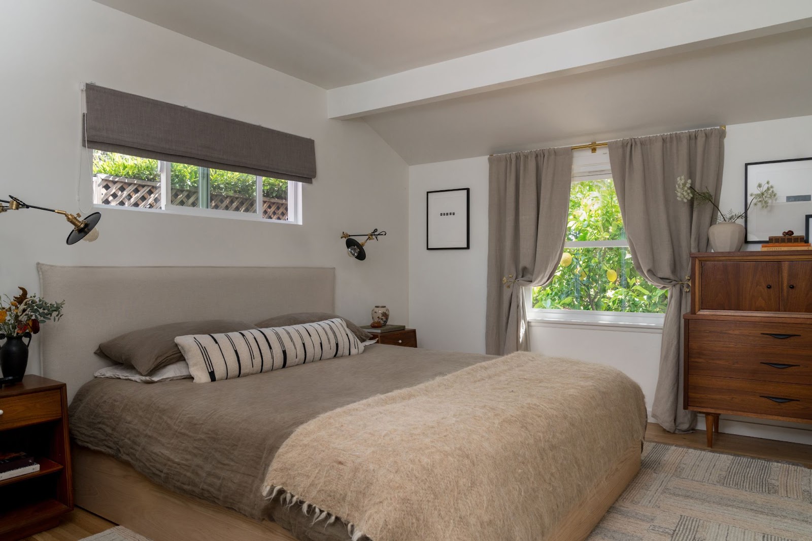 Minimalist bedroom design with neutral color palette, mid-century furniture such as nightstand and cabinet, and serene ambiance.