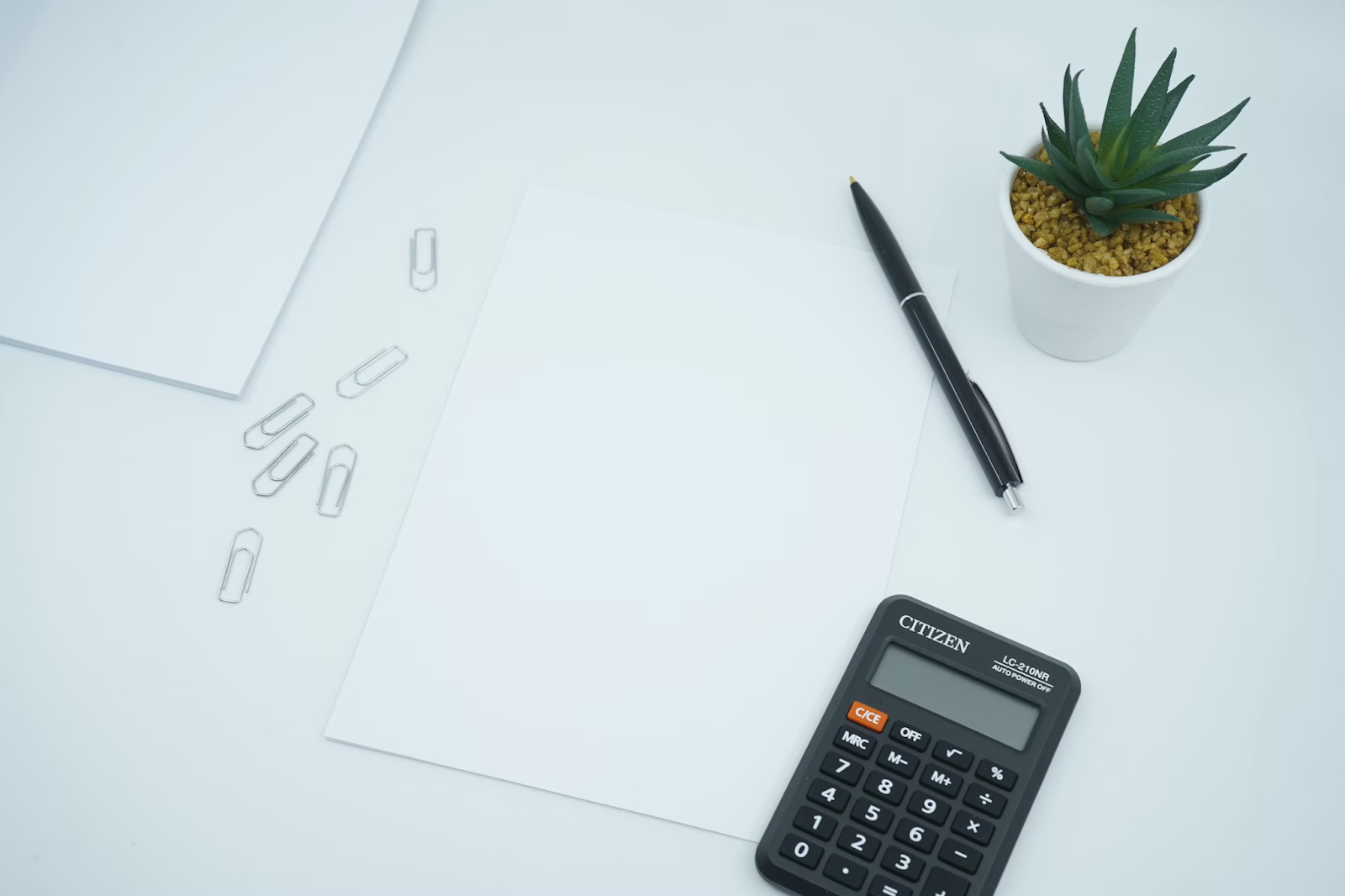 calculator pen and paper on white desk