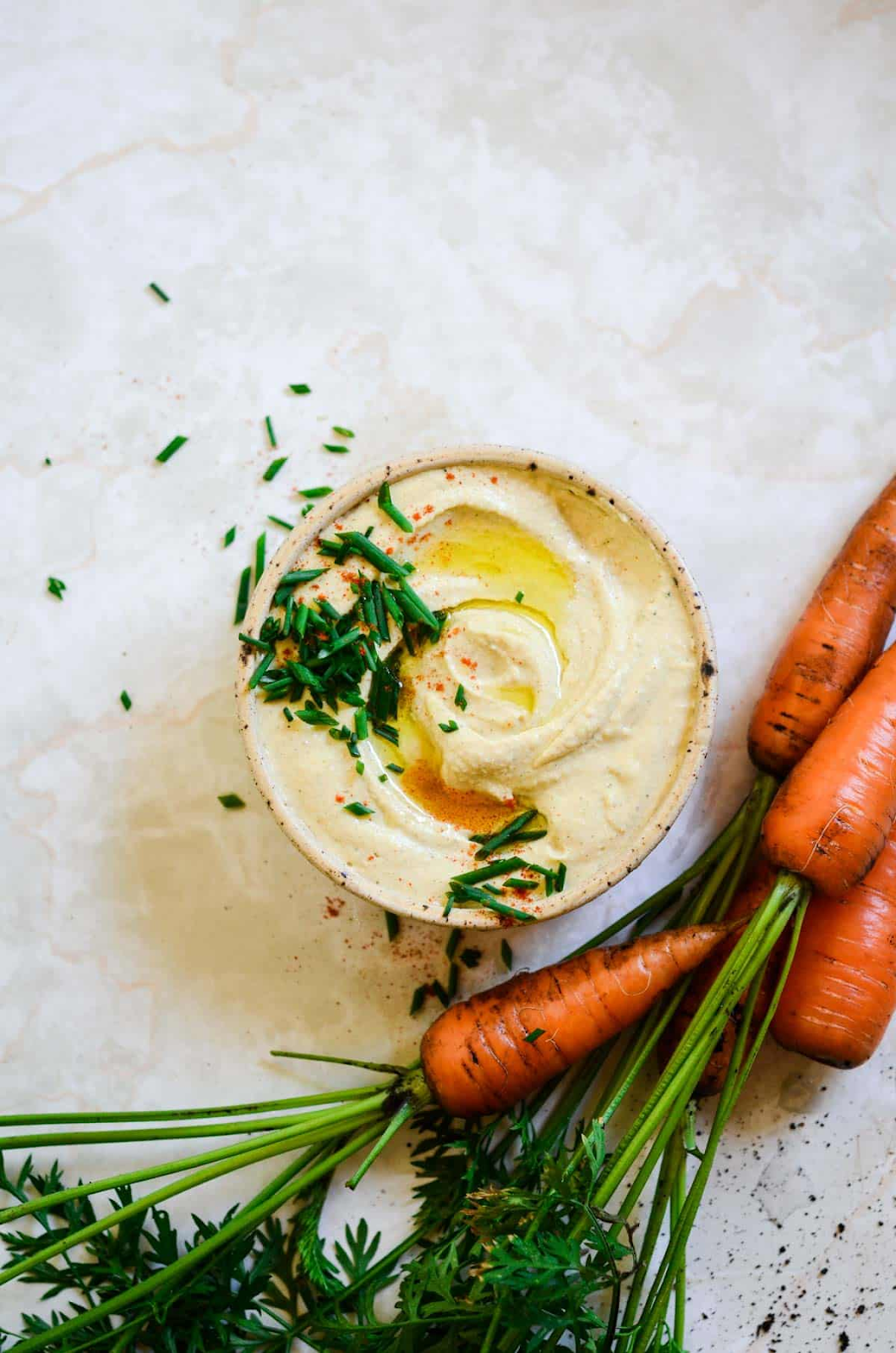 hummus in bowl beside large carrots