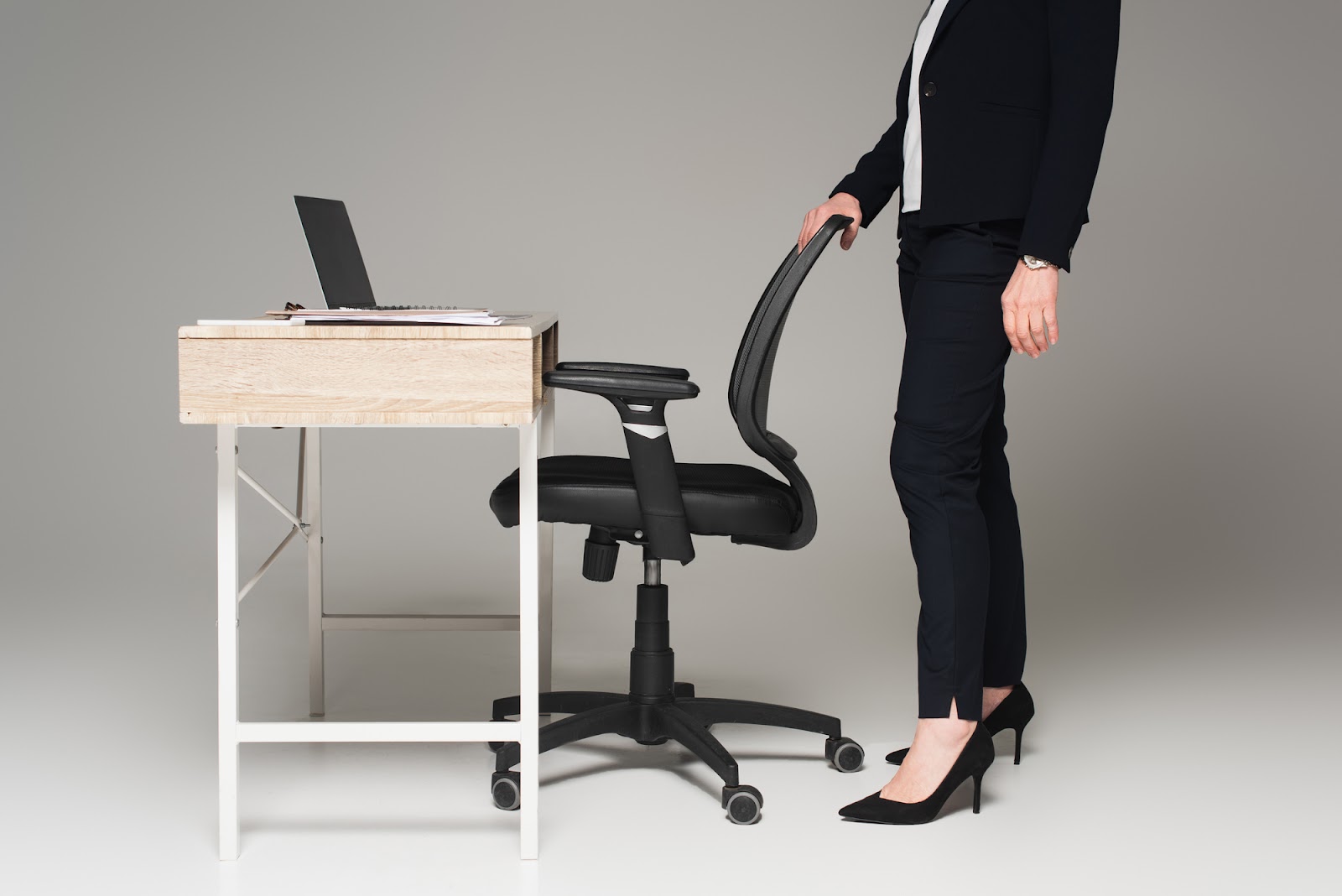 A women standing near an ergonomic office chair with office table