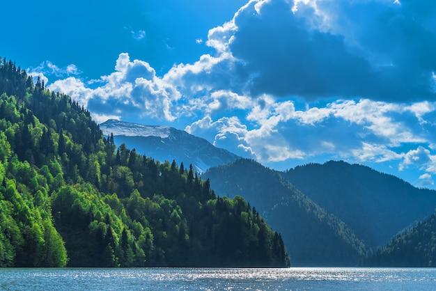 Free photo beautiful lake ritsa in the caucasus mountains. green mountain hills, blue sky with clouds. spring landscape.