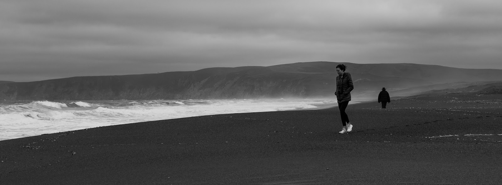 Black and white photo of the author walking on a beach.