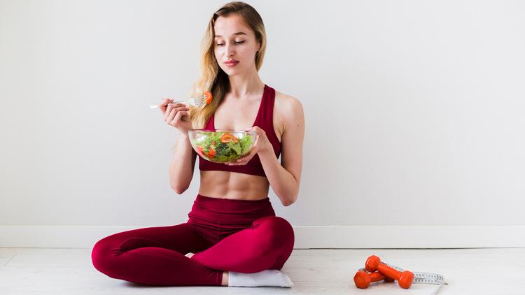 A person sitting cross legged eating a salad

Description automatically generated