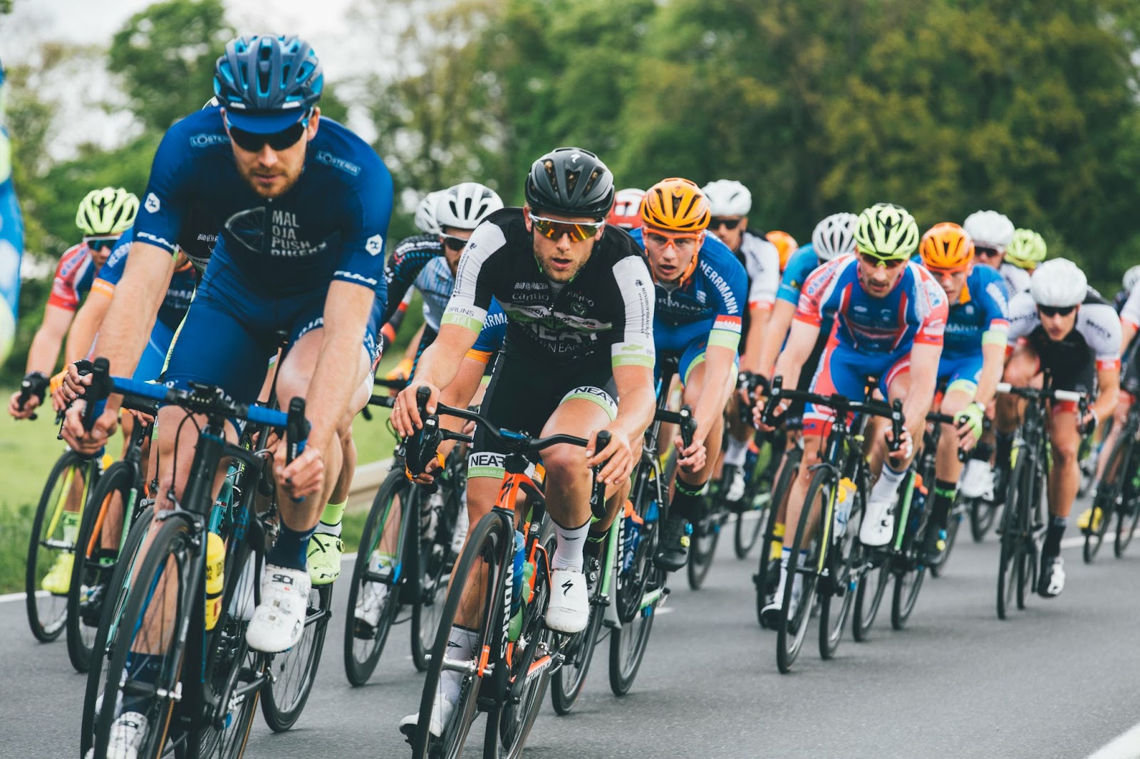 A group of road racers in various spandex cycling kit pedalling around a slight corner as seen from the front.