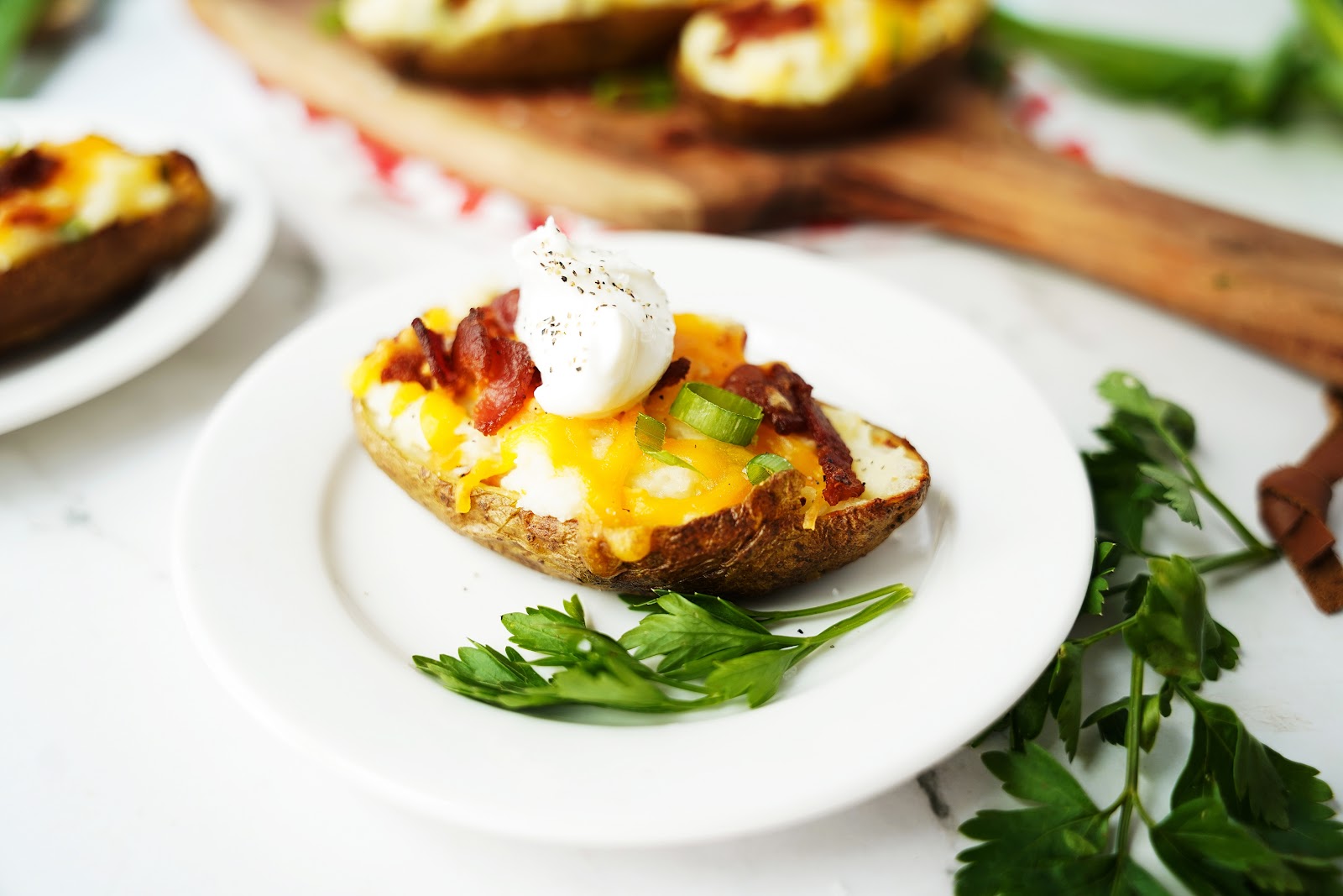 Twice baked potato on a plate with a cilantro garnish.
