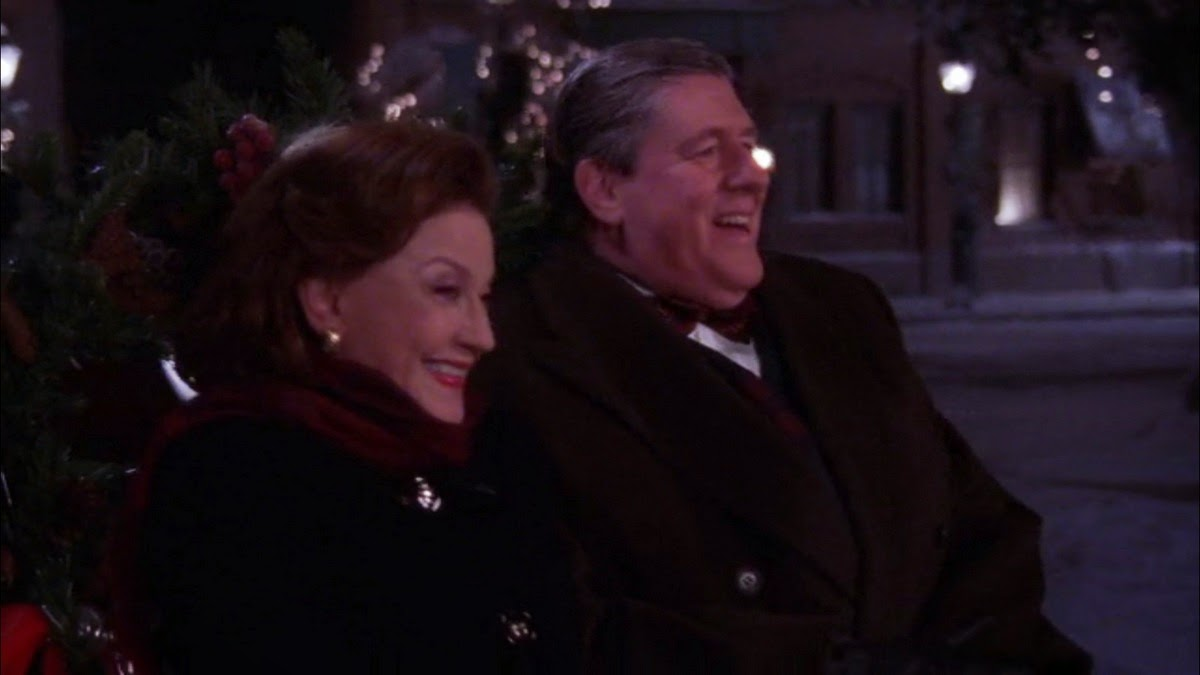 Emily and Richard sitting next to each other laughing joyously in the Bracebridge Dinner episode, one of the best holiday tv episodes ever.