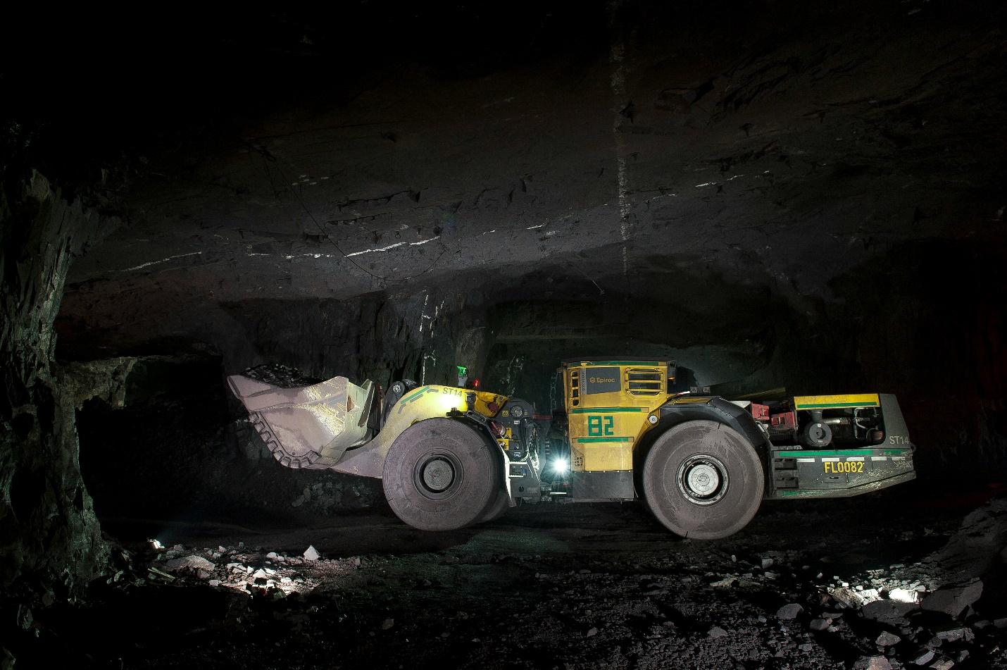 A large yellow and green vehicle in a dark cave

Description automatically generated