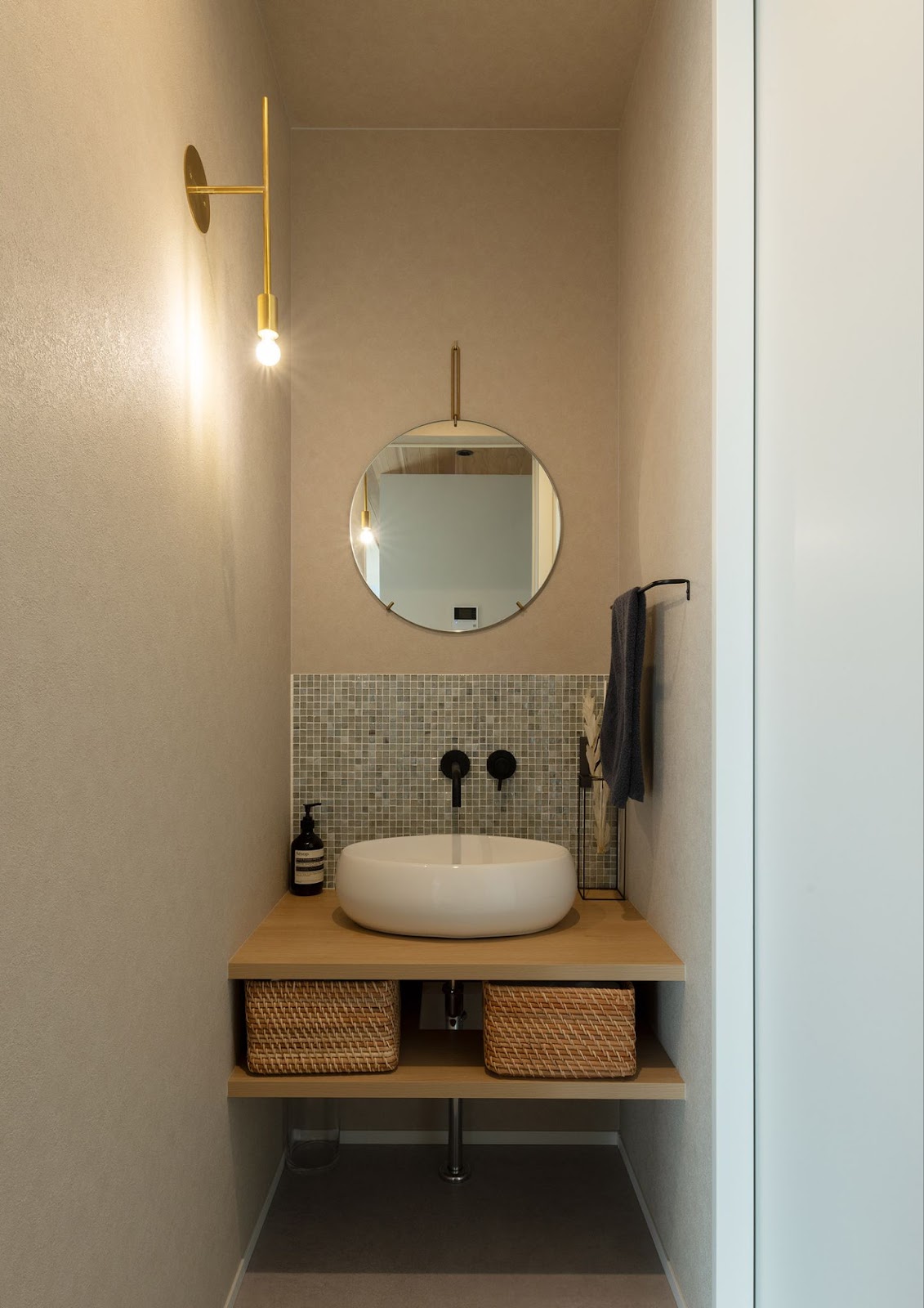壁付け水栓や丸い鏡が個性的な手洗いカウンター