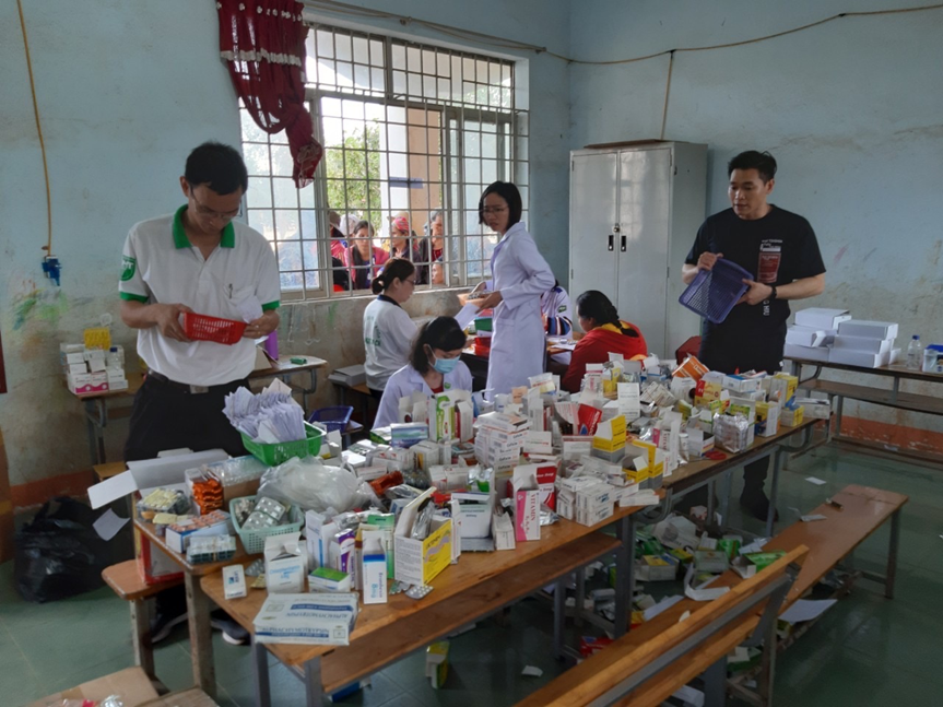 A group of people in a room with a table full of medicine
Description automatically generated