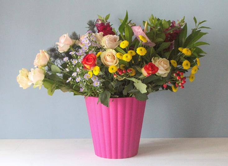 Fresh cut flowers sitting in a pink plastic bucket