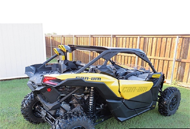 A Can-Am Maverick X3 with a 3" Snorkel Kit by SYA Warrior Riser installed, parked on grass in a fenced area.