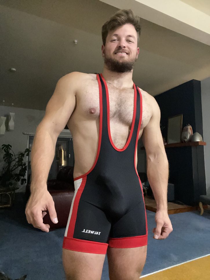 Max Small smiling for a selfie wearing an athletic wrestling singlet in red and black with white accents