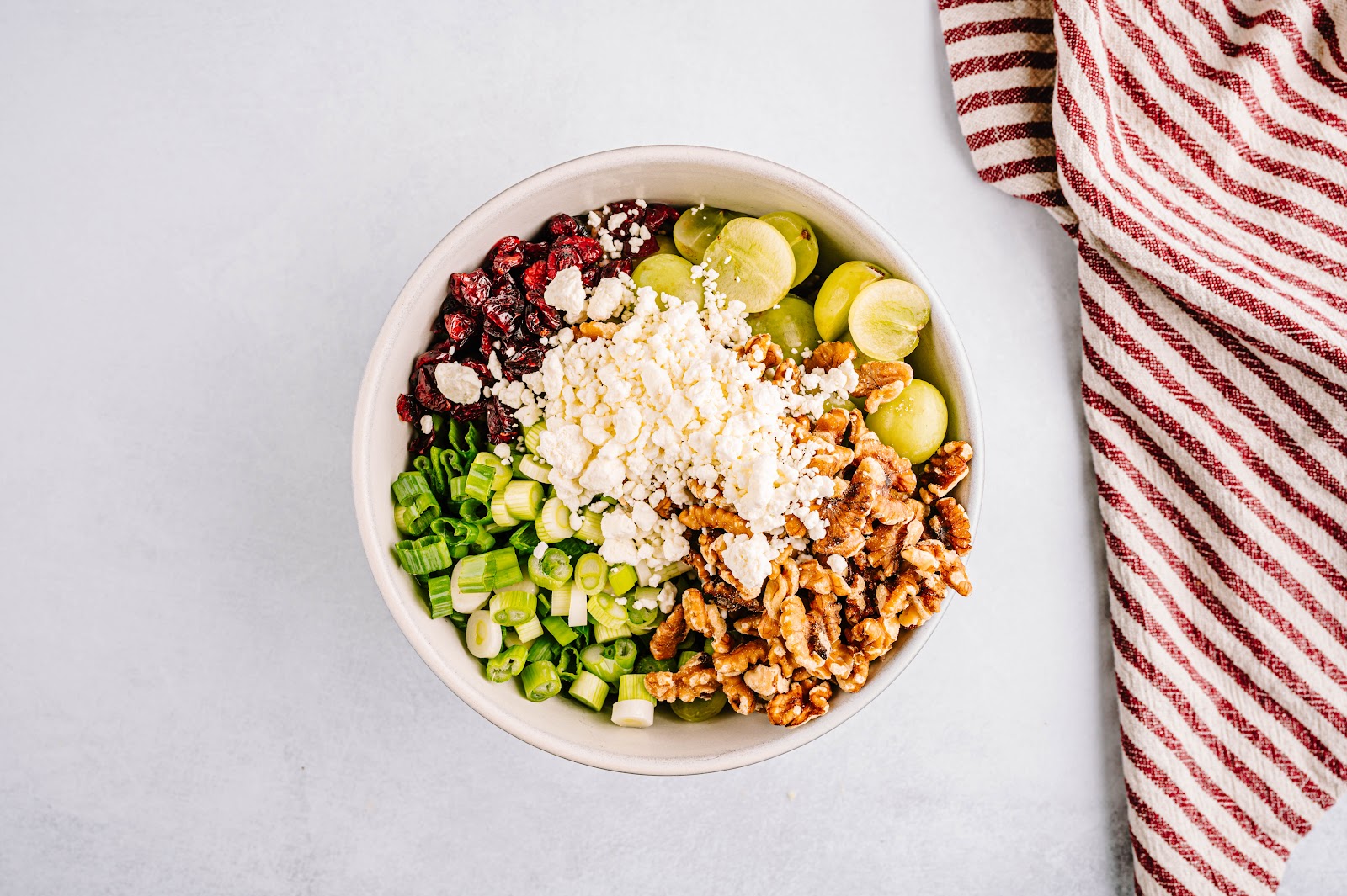 Add rice, grapes, scallions, cranberries, walnuts, and goat cheese to a serving bowl and mix. 