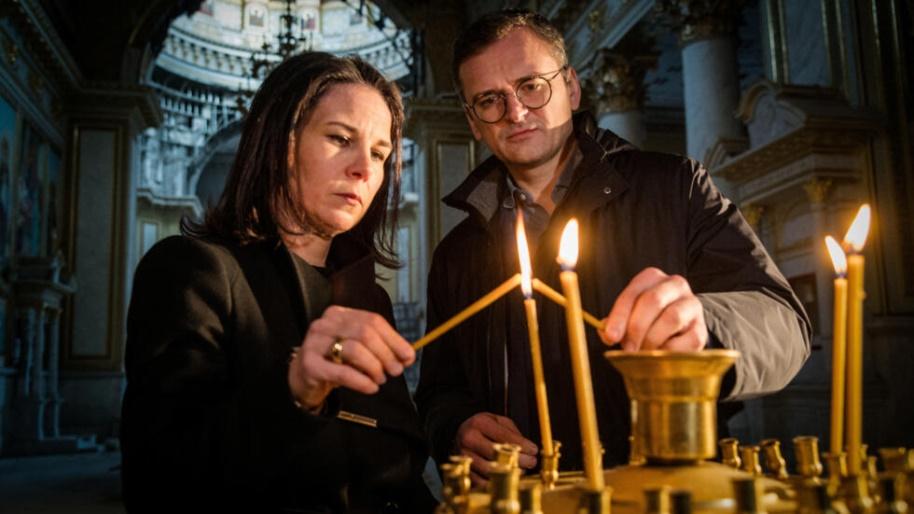 Germany's Foreign Minister Annalena Baerbock and Ukrainian counterpart Dmytro Kuleba light candles as they visit the Transfiguration Cathedral, damaged last year by a Russian missile strike, on the se
