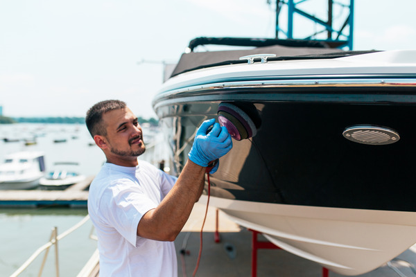 Marine mechanic using orbital polisher for boat maintenance in a marina