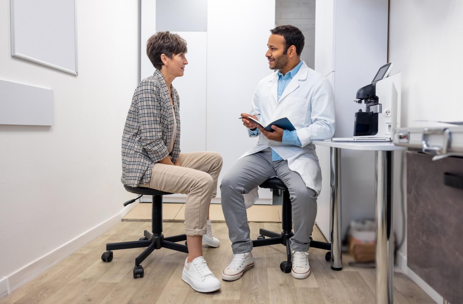 A woman sits across from an optometrist in his office, discussing her eye health.