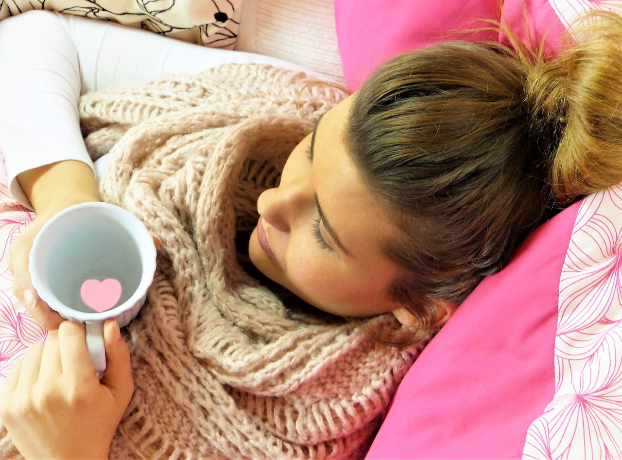 young woman lying back on cushions, eyes closed, holding mug of water, lacking in energy without a fast like a girl cheat sheet infrographic to help guide her
