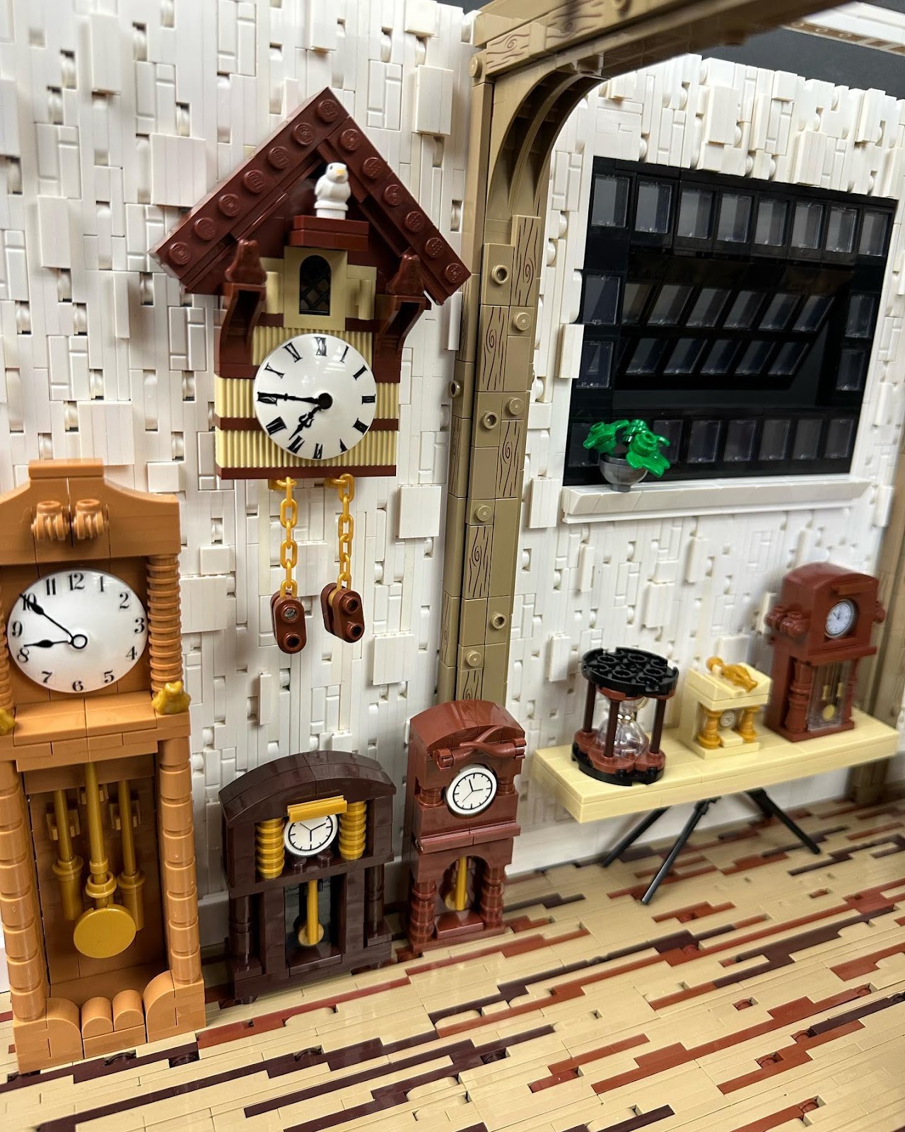 A close-up photograph of Kelly's LEGO creation Clockmaker's Studio, showing several grandfather clocks, pendulum clocks and a cuckoo clock