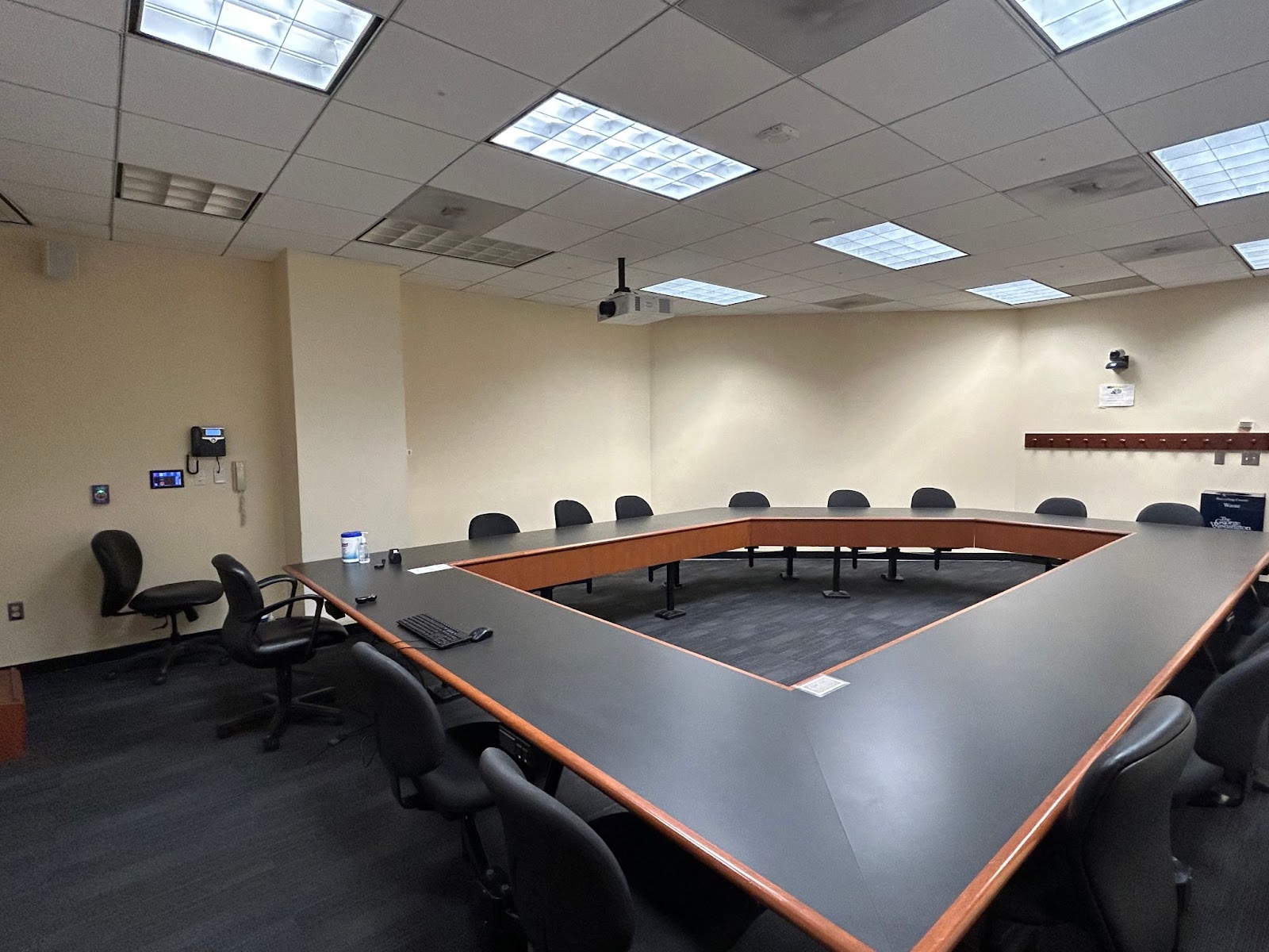 View from the front of the room: Camera, keyboard and mouse, hotline phone, touch control panel, projector.