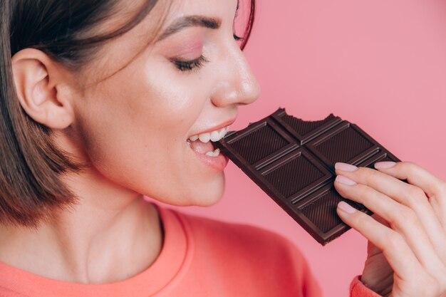 Mulher comendo uma barra de chocolate, rica em cacau