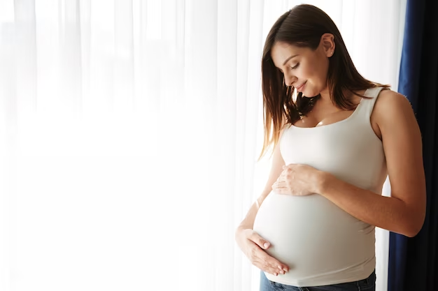A smiling pregnant woman touching her belly.
