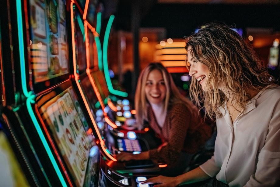 A picture of two women playing on slots machine at a casino. 