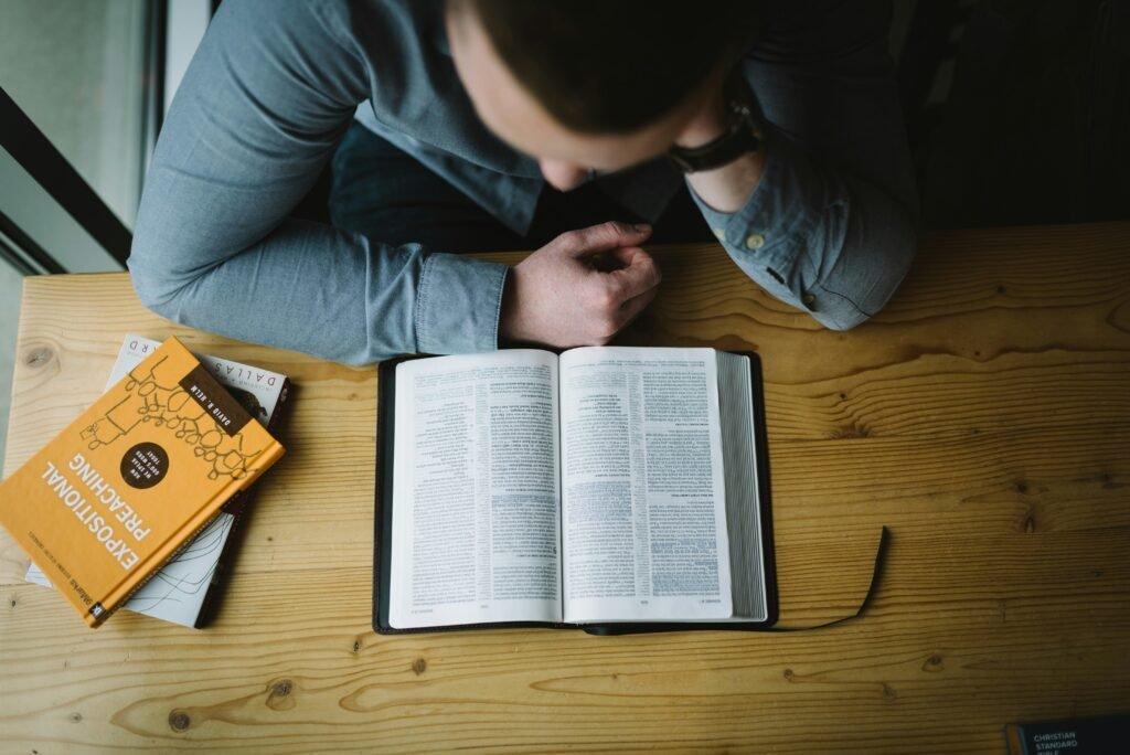 person on his study desk completing a book - How To Improve Study Habits