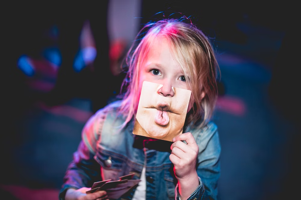 a child holding a picture of a pout in front of his face