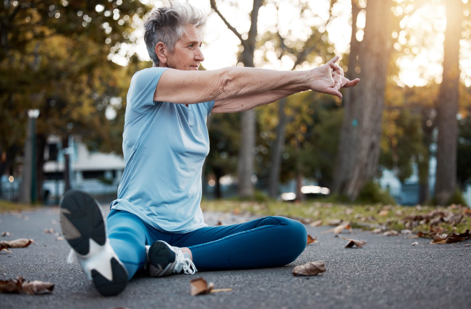 A senior woman in her sportswear stretching outdoors.

