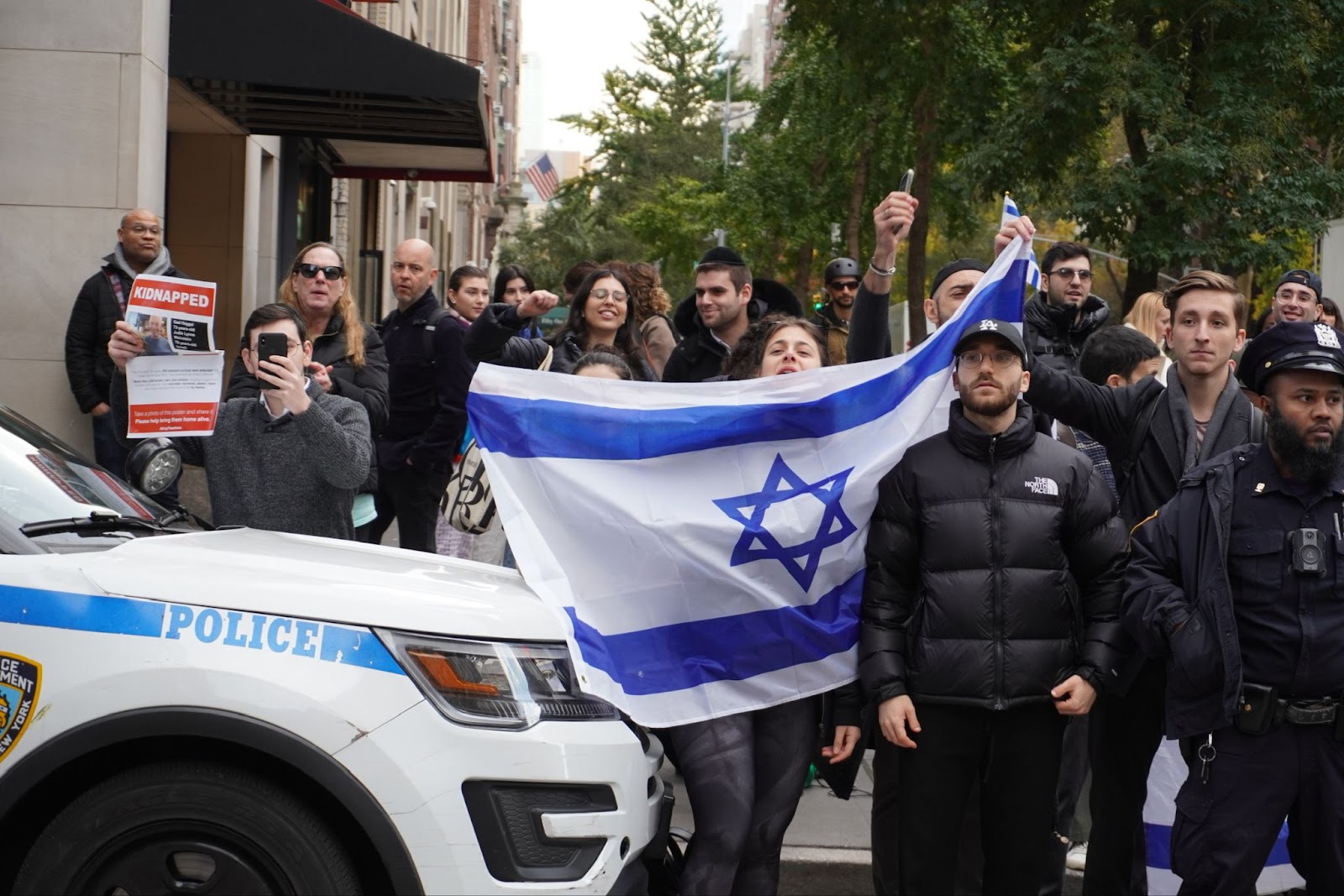 People gathered across from the University Center on East 13th St, holding up an Israeli flag.