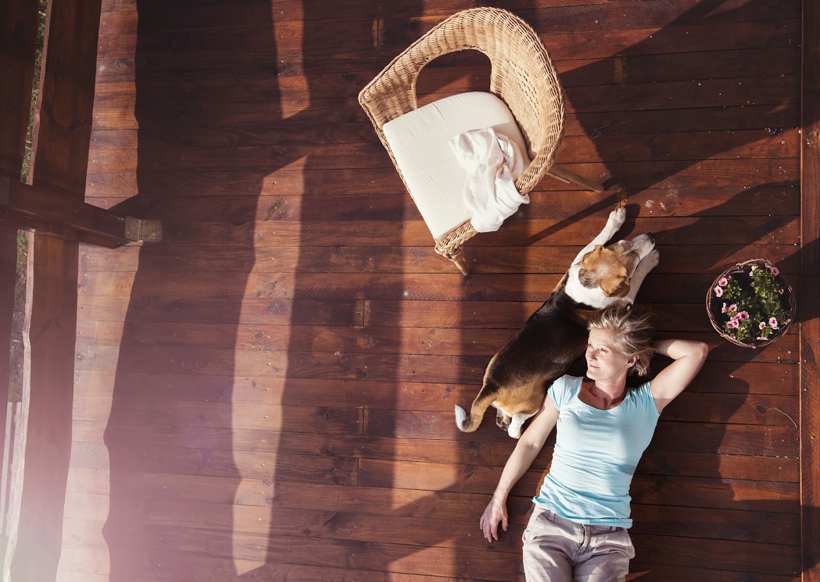  An aerial view of a senior woman and her dog lying down on a hardwood floor. 