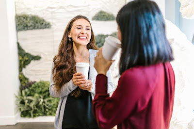Two women laughing over coffee.