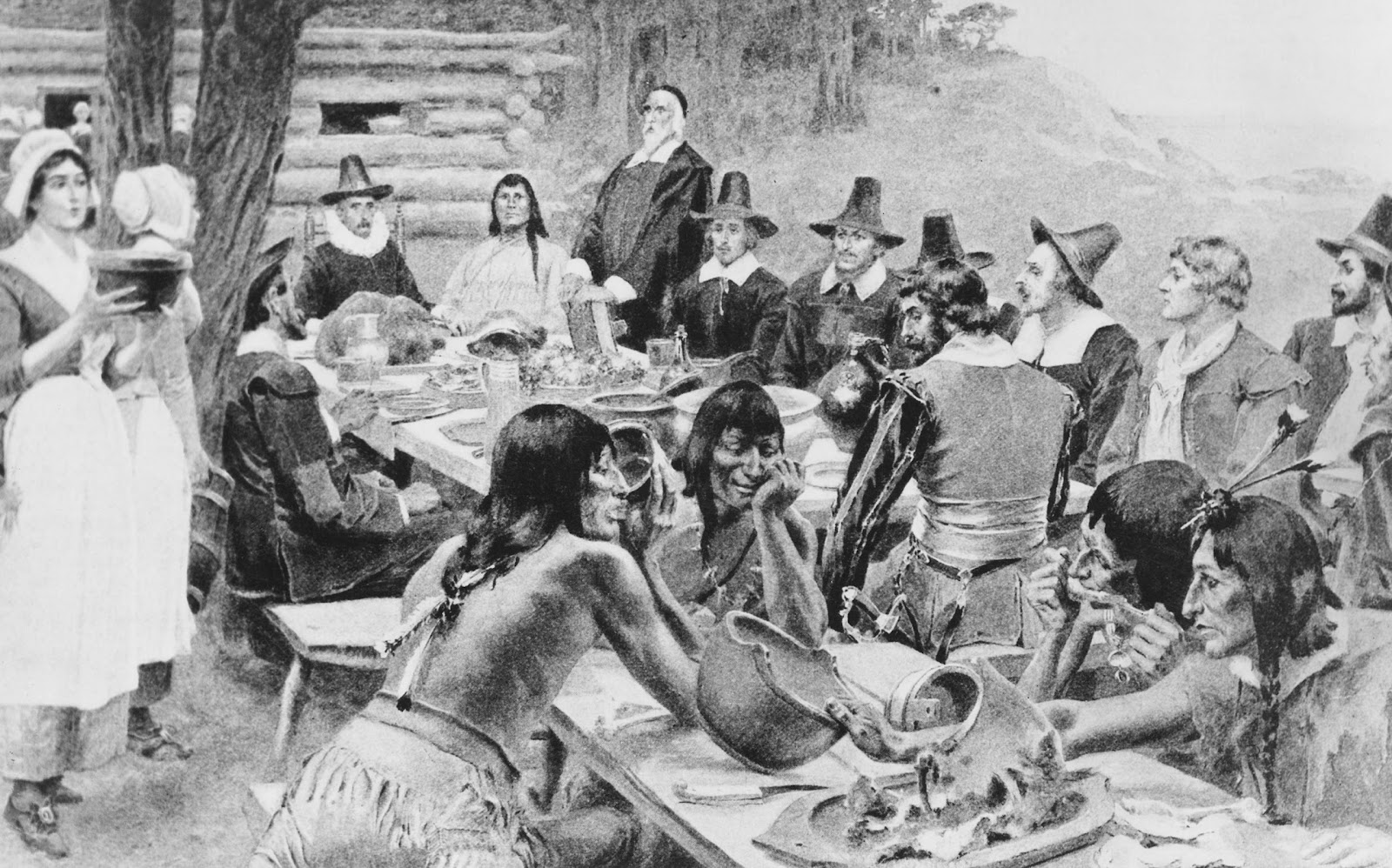 Tranh vẽ mô tả những người định cư ban đầu ở Thuộc địa Plymouth đang chia sẻ bữa tiệc Tạ ơn mùa màng với các thành viên của bộ tộc Wampanoag địa phương tại Đồn điền Plymouth, Plymouth, Massachusetts, 1621. (Ảnh: Frederic Lewis/Archive Photos/Getty Images)