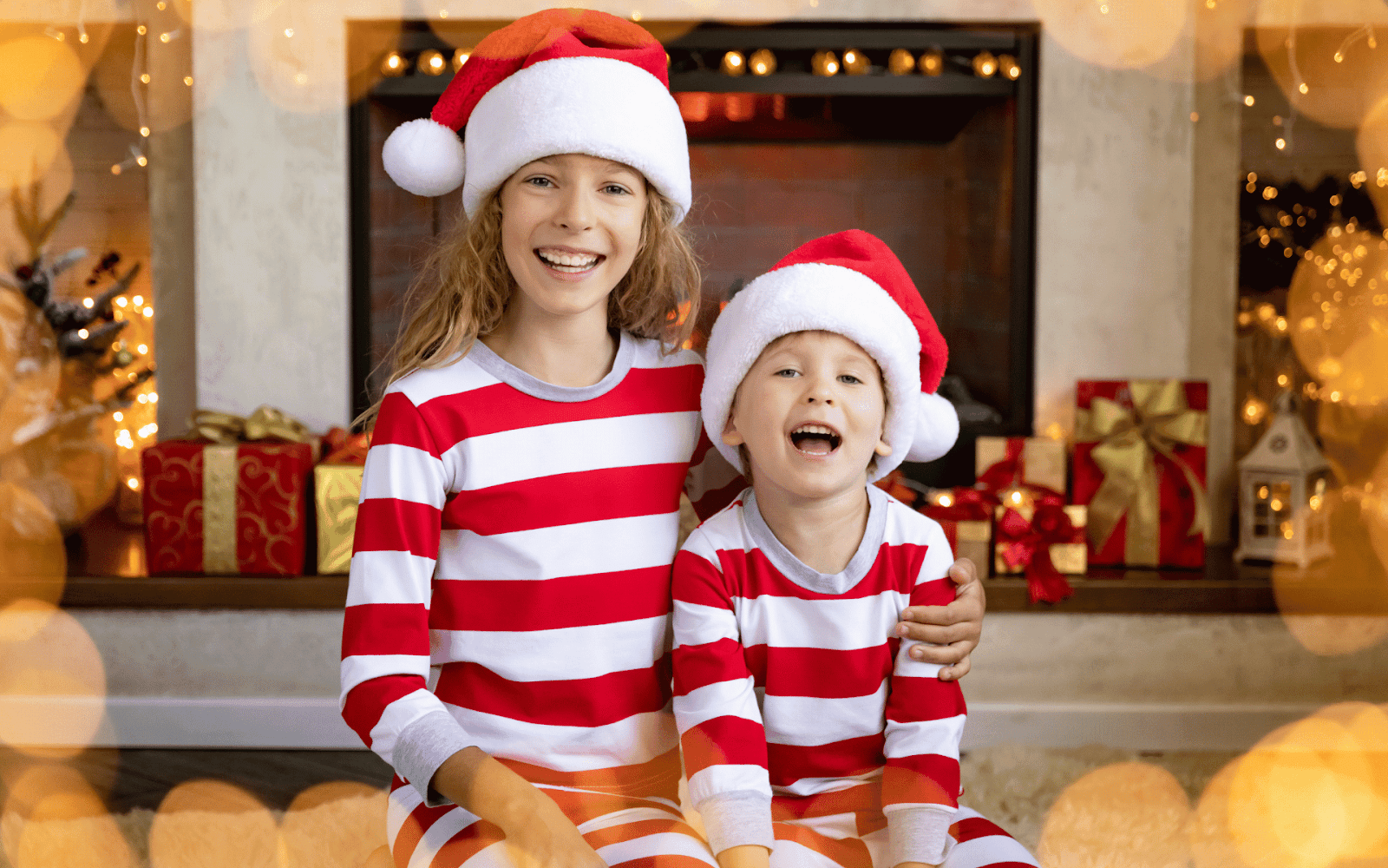 Two children wearing matching pajamas and santa hatsDescription automatically generated