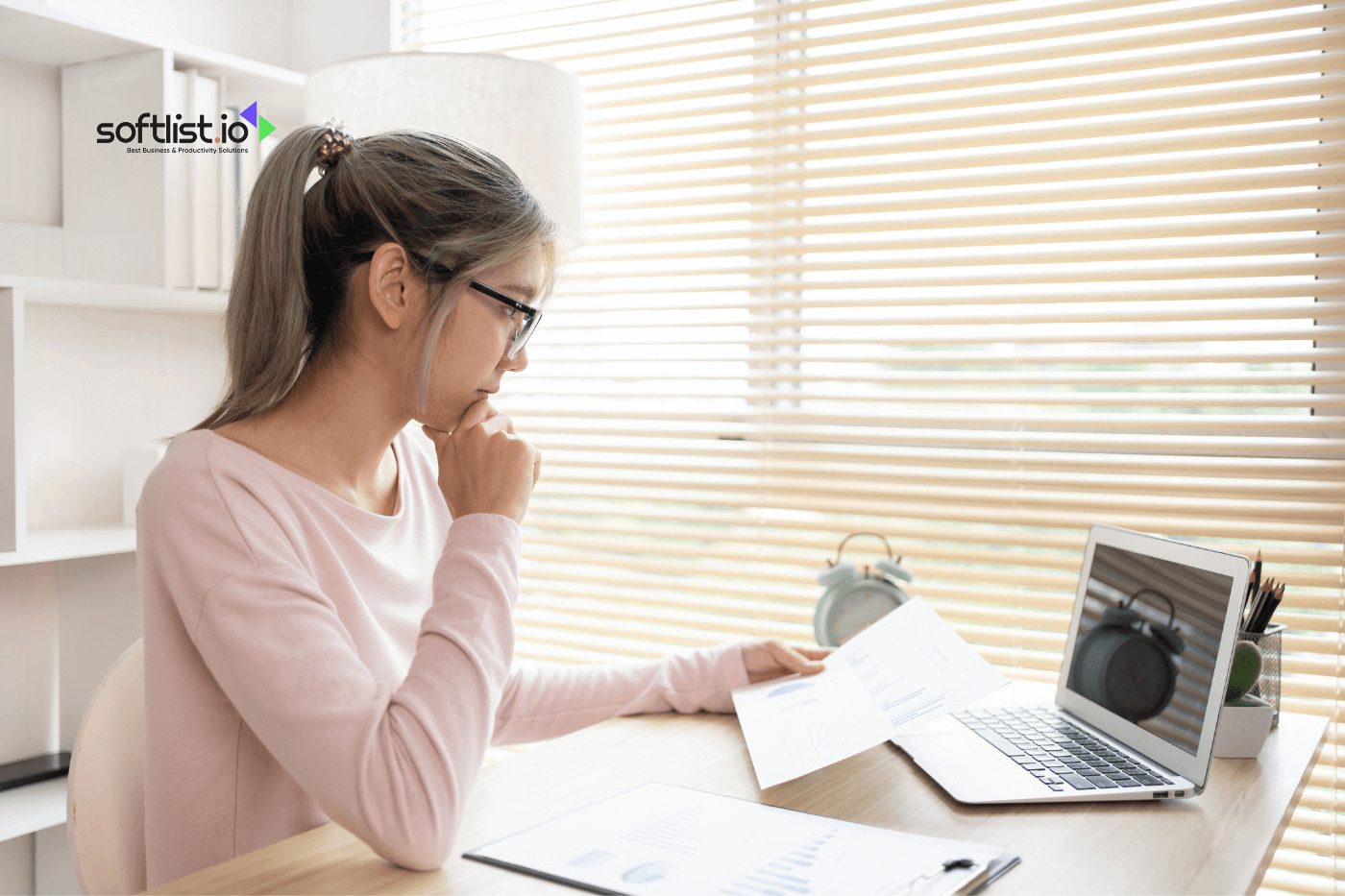 a woman checking her laptop and holding a paper