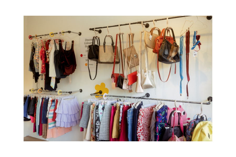 Clothing racks of colourful clothes and accessories from a thrift store.