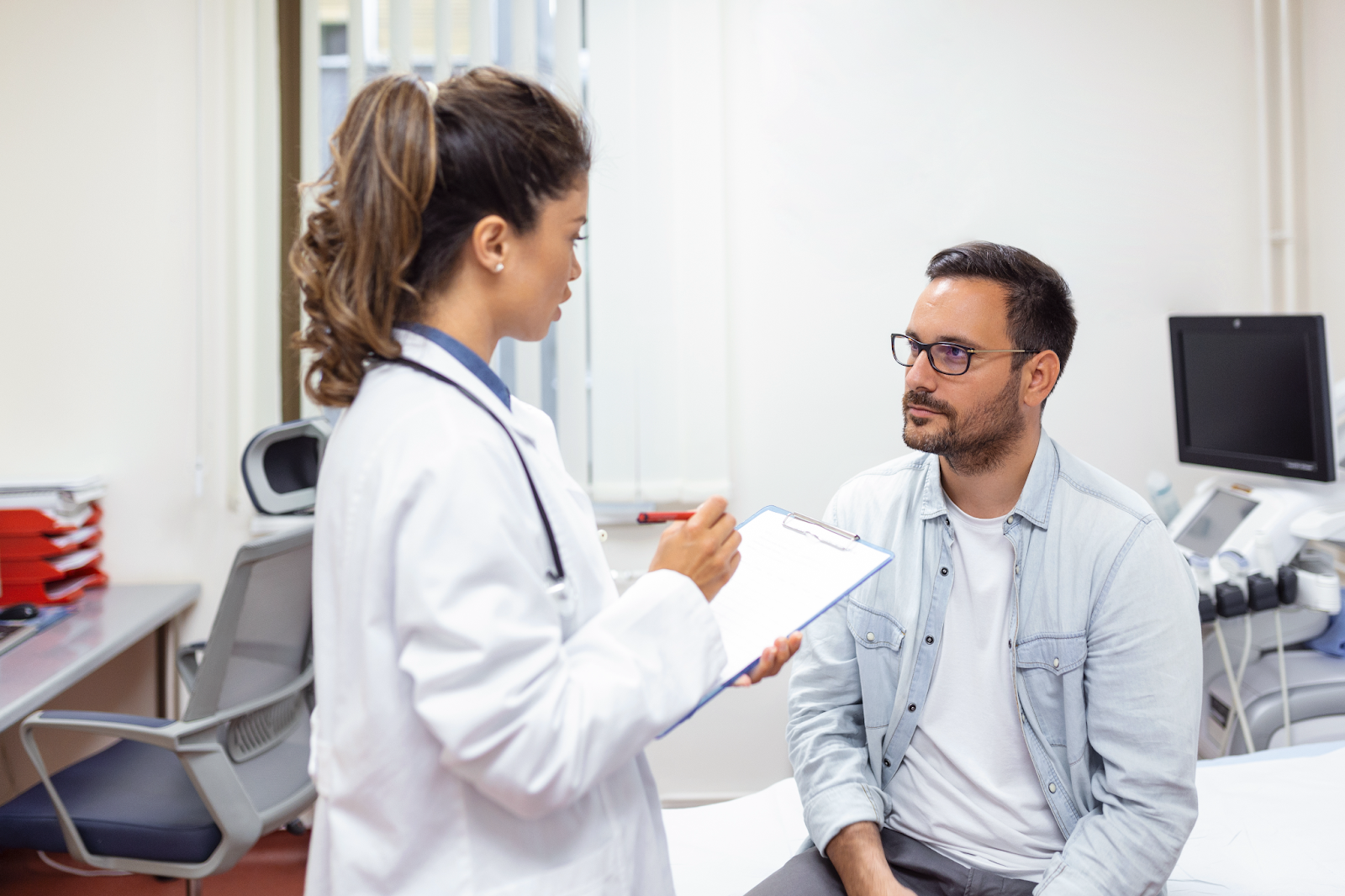 homem sentado no consultório médico com uma médica explicando seu diagnóstico