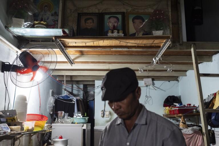 After wrapping up his work for the day, Pham Van Sang, a street food vendor originally from the Mekong Delta, stands near a small altar honoring his ancestors in his apartment in Ho Chi Minh City, Vietnam, Monday, Jan. 22, 2024. Pham earns his living by selling noodles in the city's industrial zone, a destination for many migrants from the Mekong Delta seeking a brighter future. (AP Photo/Jae C. Hong)