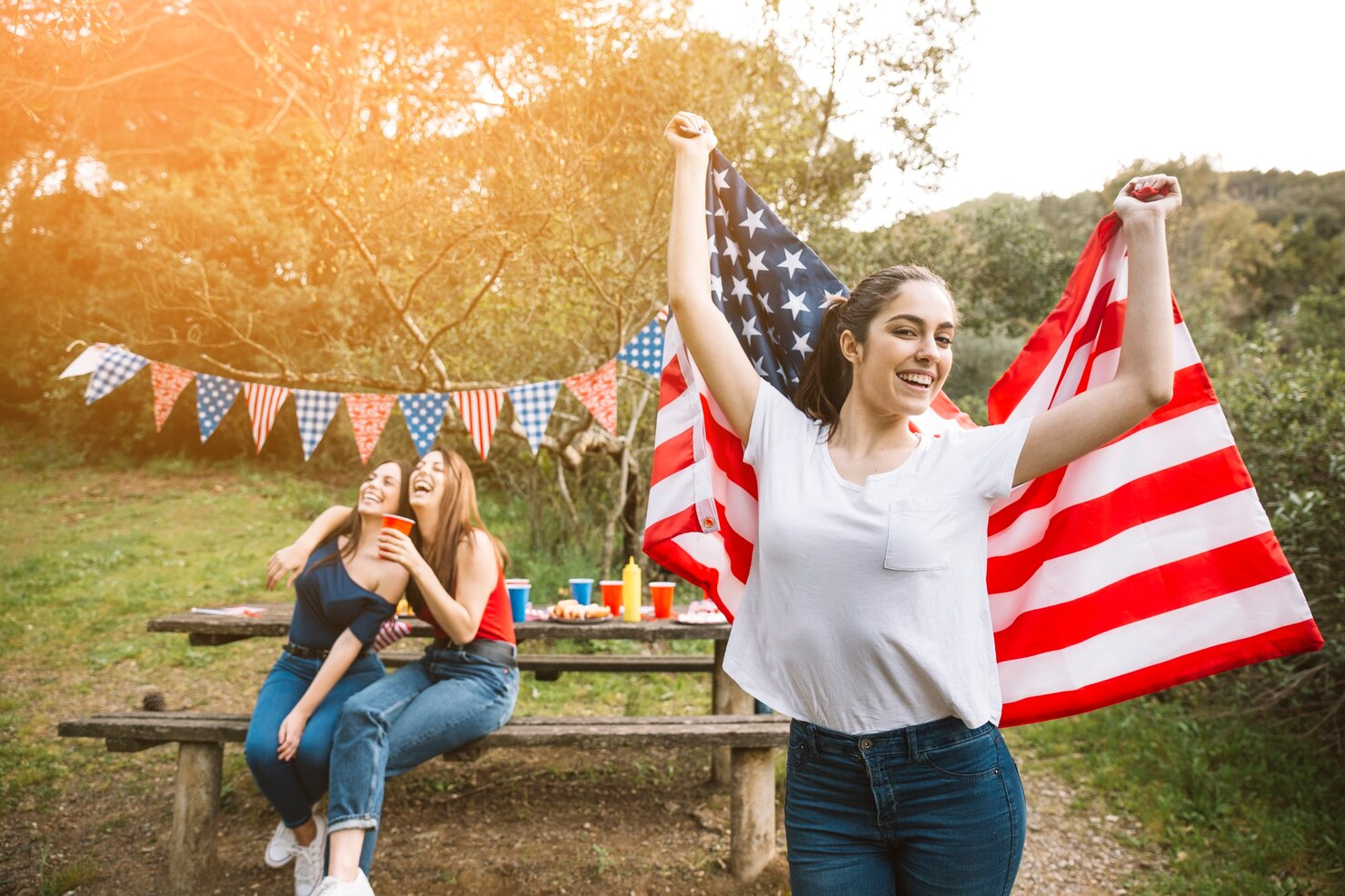 Friends celebrating 4th of July holding American flag. 