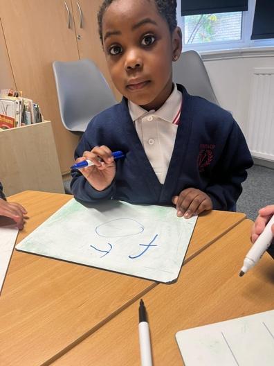 A child sitting at a table with a pen and paper

Description automatically generated